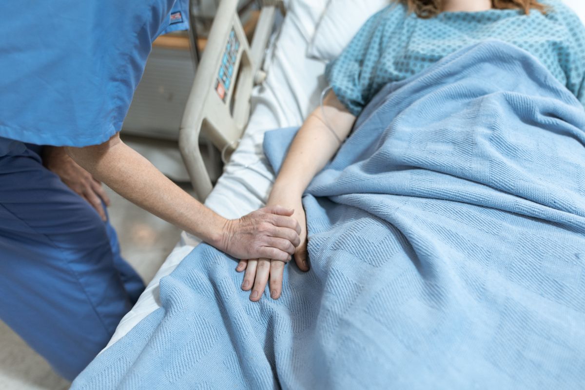 Ensihoitaja auttaa iäkästä potilasta ambulanssin luona