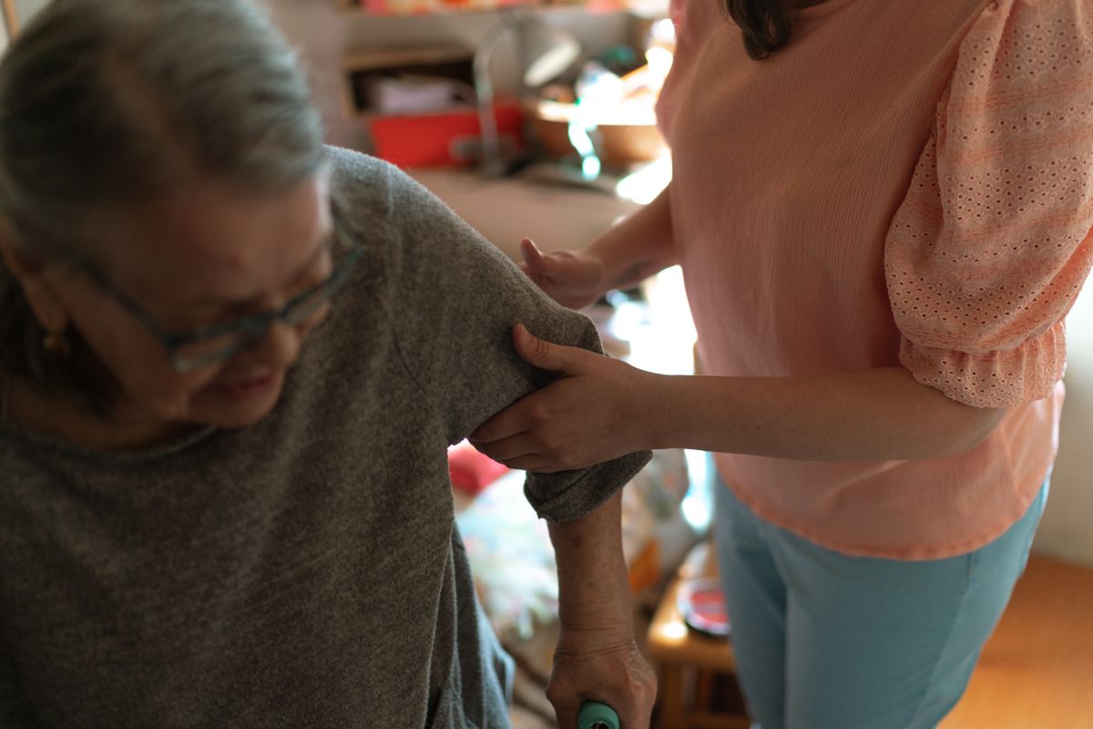 Aidante aidant une femme âgée à se relever à son domicile