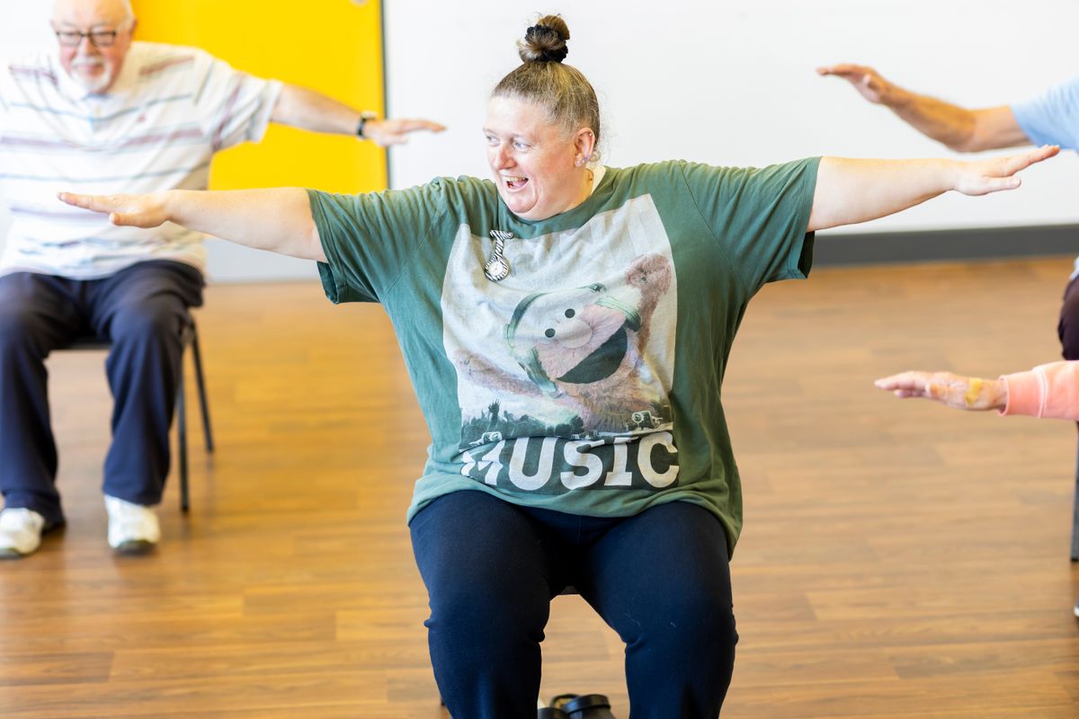 Groupe de personnes âgées faisant des exercices assises dans un cours d’activité physique