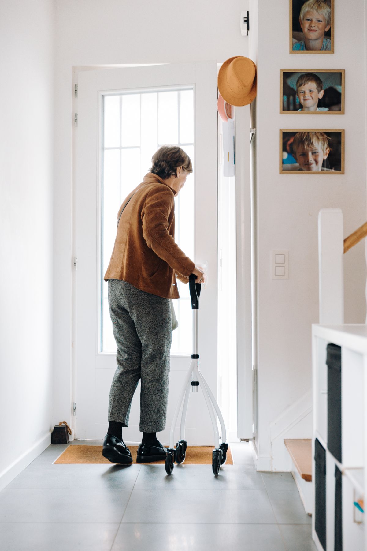 Femme âgée avec un déambulateur dans l’entrée de sa maison, à côté d’un tapis d’entrée