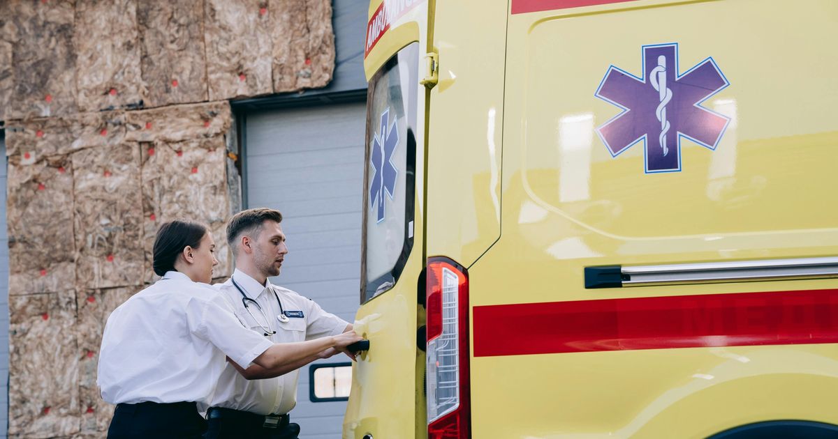Two healthcare technicians by the rear door of an ambulance