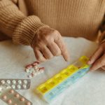 Ältere Person sortiert ihre Medikamente in einer Wochenpillendose